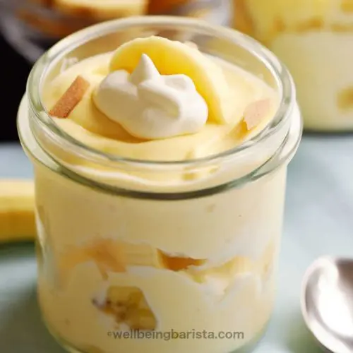 A small jar with healthy banana pudding with greek yogurt with some banana pieces in middle and top layer and a little yogurt on top as decoration