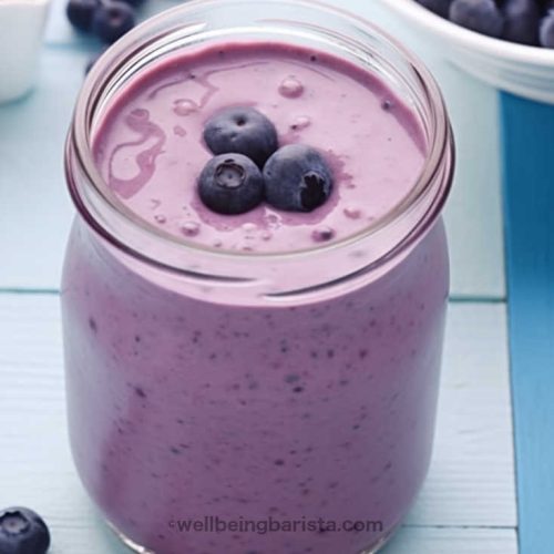 A jar with a mix of strawberry and blueberry smoothie with a few strawberries on top.