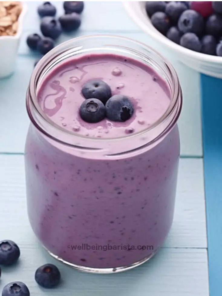 A jar with a mix of strawberry and blueberry smoothie with a few strawberries on top.