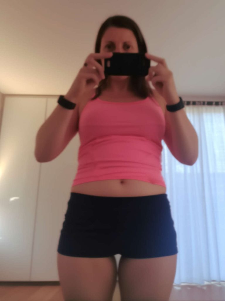 A mirror selfie of someone in a cropped shirt and shorts, showing progress from tiny habit changes.