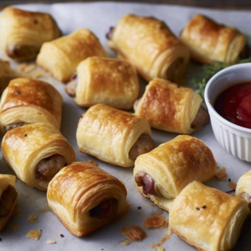 mini British sausage rolls with sausage meat and puff pastry served with ketchup.