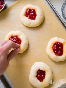 Placing jam into each small hole of the jam buns.