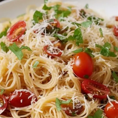 Summer garden pasta salad with angel hair, halved cherry tomatoes, fresh basil, and grated Parmesan inspired by Ina Garten
