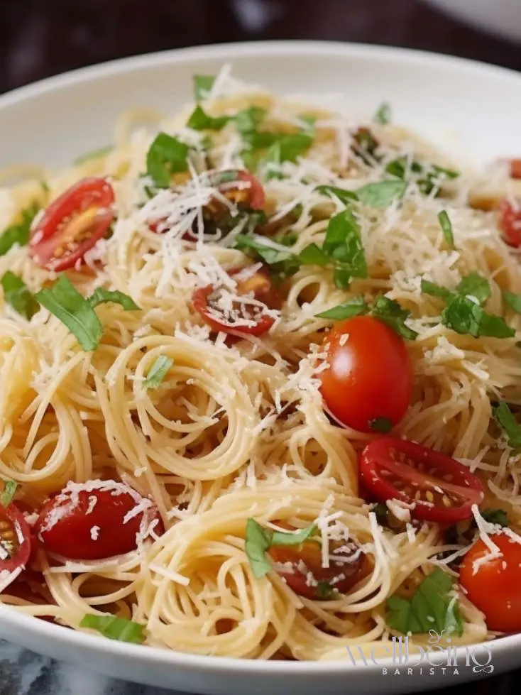 Summer garden pasta salad with angel hair, halved cherry tomatoes, fresh basil, and grated Parmesan inspired by Ina Garten