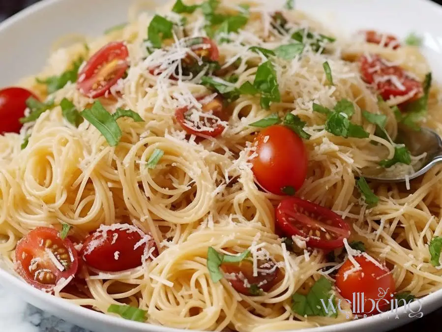 Summer garden pasta salad with angel hair, halved cherry tomatoes, fresh basil, and grated Parmesan inspired by Ina Garten