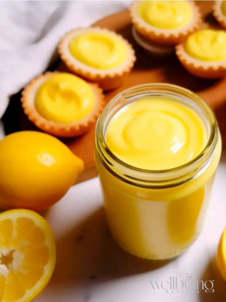 lemon curd sauce in a jar with portuguese tarts filled with lemon curd.