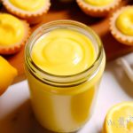 lemon curd sauce in a jar with portuguese tarts filled with lemon curd.