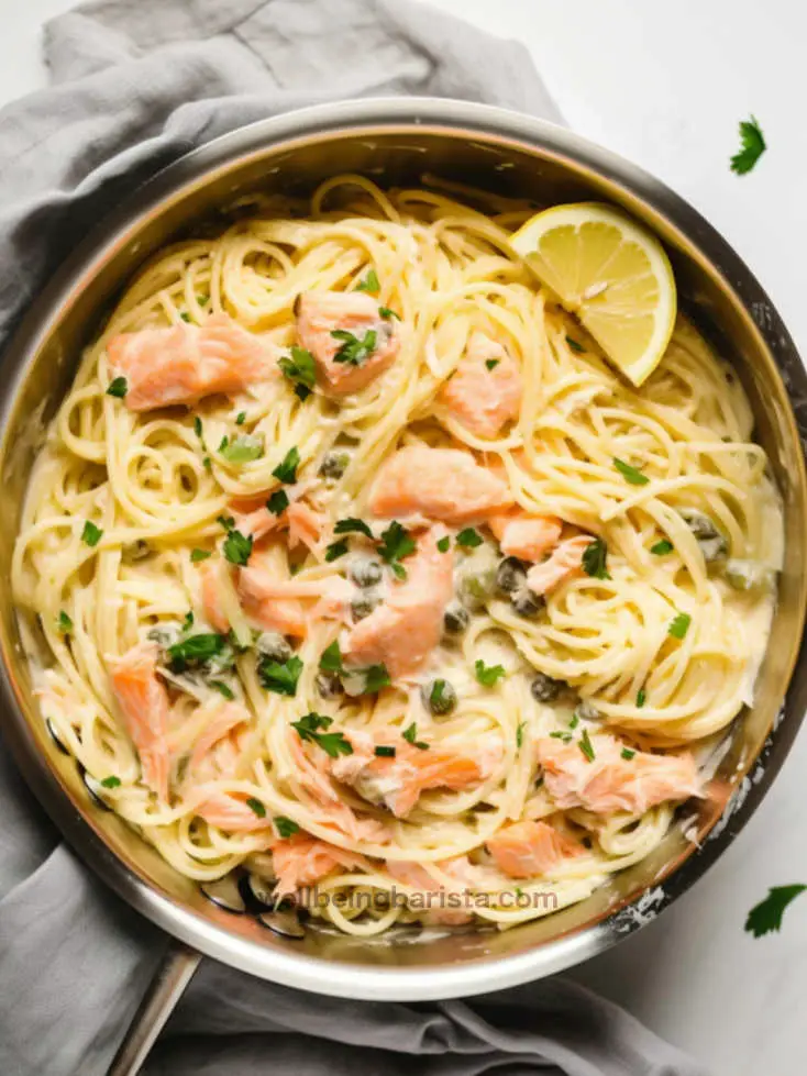 a pan with smoked salmon linguine with capers and parsley, chives and lemon to garnish.
