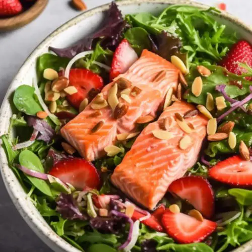 grilled salmon summer salad with strawberries on a bed of green salad